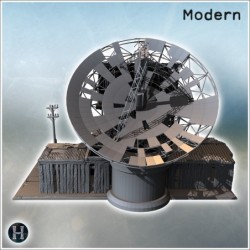 Satellite dish with adjacent structures, barrels, and fortified surroundings in rugged terrain (4)